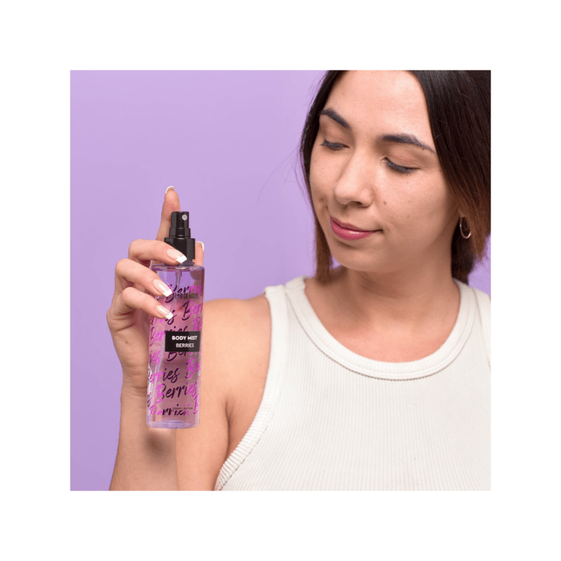 Mujer aplicando body mist de frutos rojos Flor de Mayo con fragancia fresca y dulce