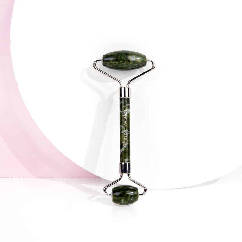 Rodillo de jade Brushworks sobre fondo neutro para rutina de cuidado facial